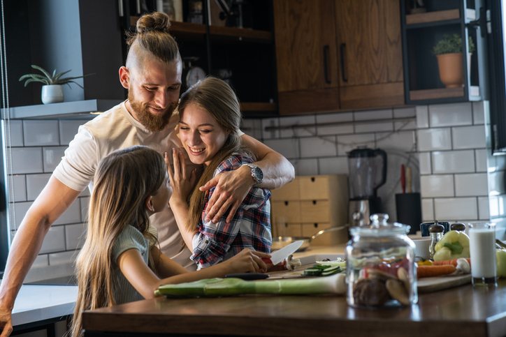 A veteran with his spouse and teenage daughter in the kitchen, an everyday domestic moment.